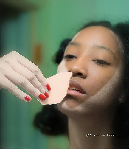 Black Woman brushing off or applying white makeup